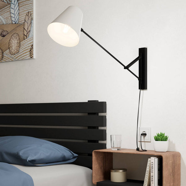 A white cone-shaped wall light with an adjustable black arm, mounted above a wooden bedside table.