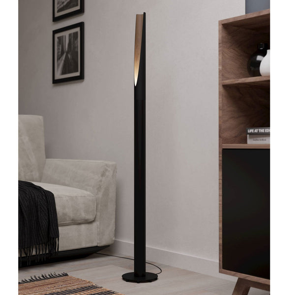 A black and wood floor lamp illuminating a modern living room setting.