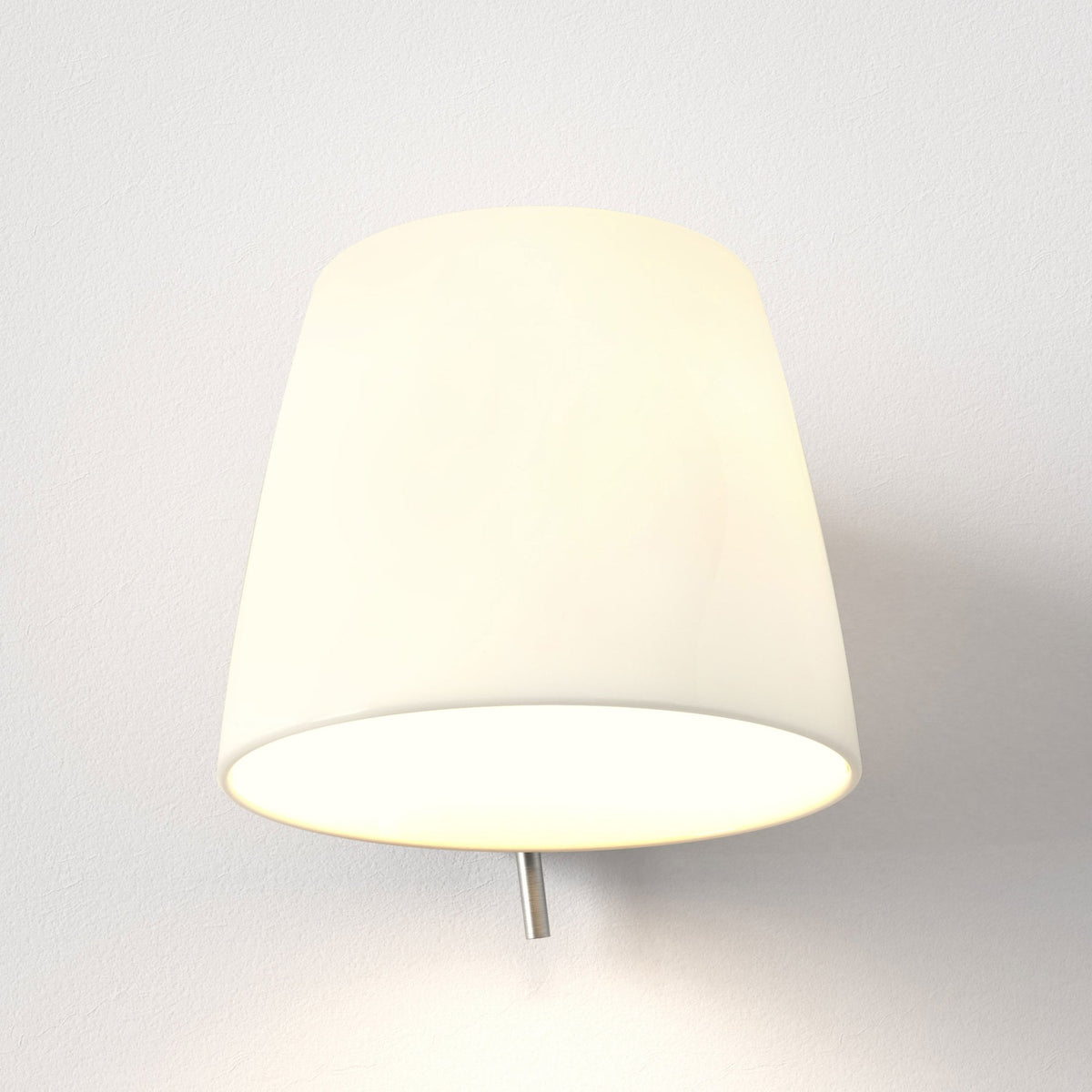 White wall sconce with a conical shade, emitting a warm glow downwards and onto the textured white wall