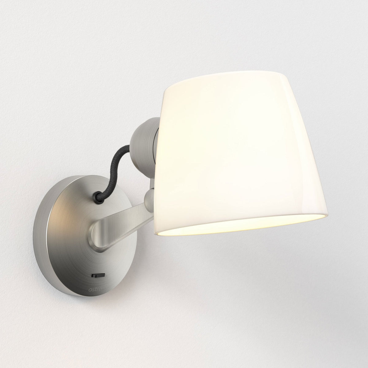Brushed nickel wall light with a white conical shade and a black braided cord