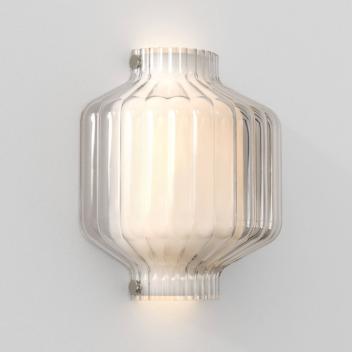 Ribbed glass wall light with a glowing bulb inside, mounted on a white wall