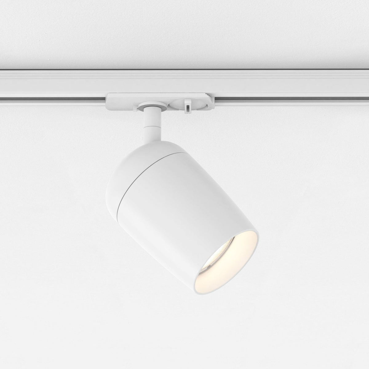 White cylindrical track light fixture with a warm glow, mounted on a white track
