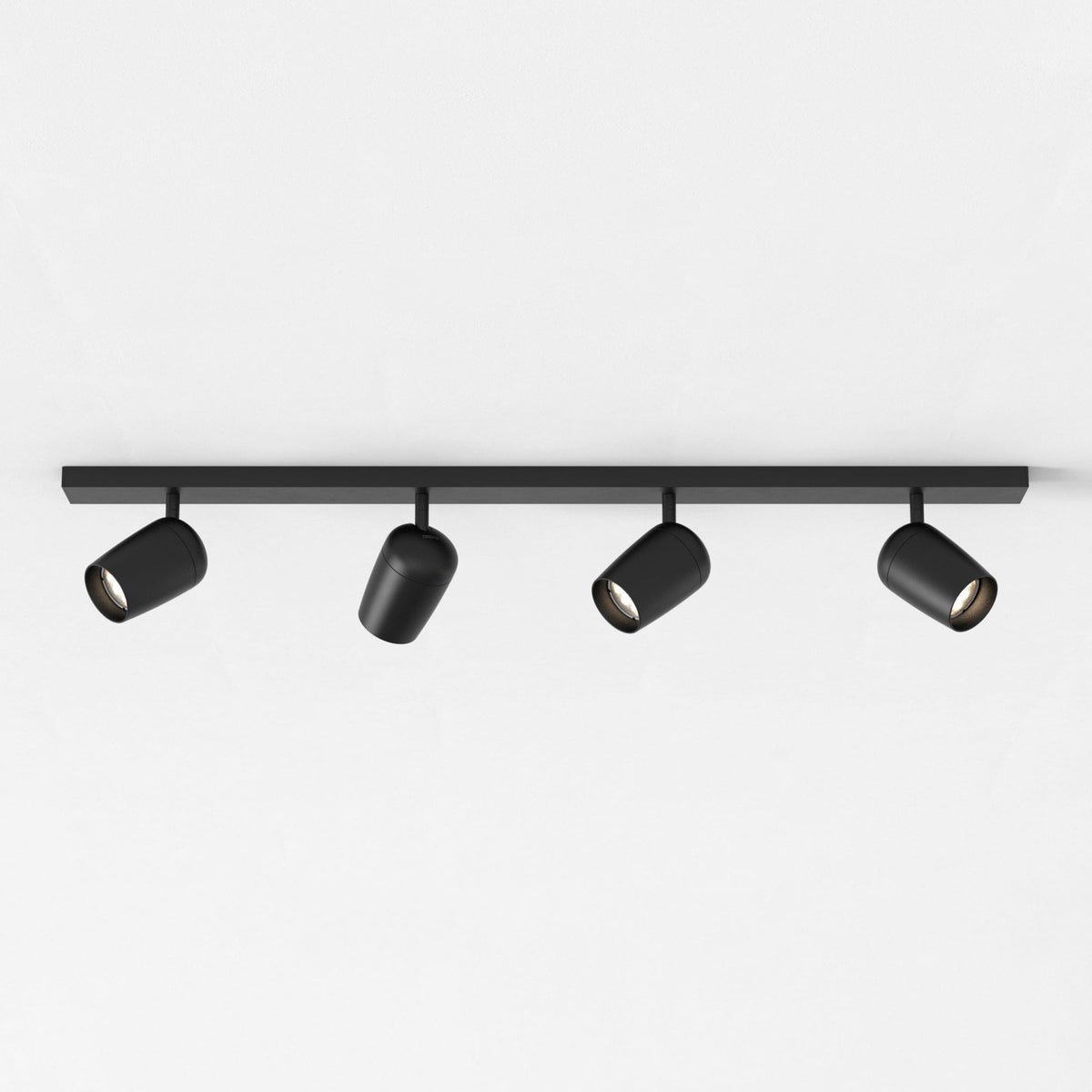 Four black track lights on a black bar against a white ceiling