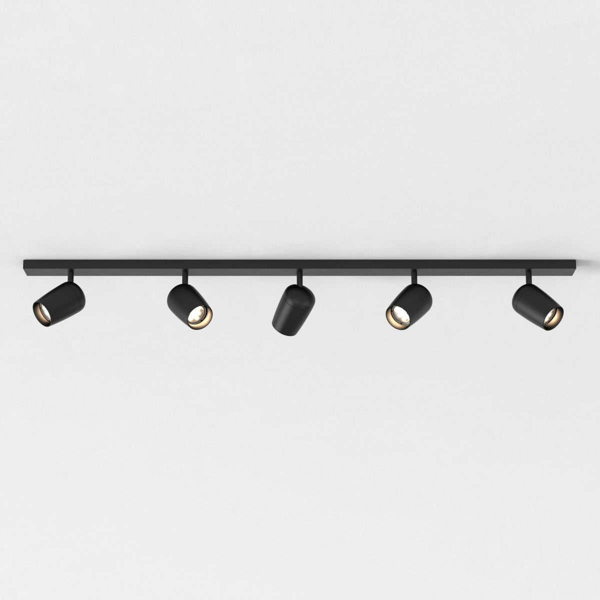 Five black track lights on a black track against a white ceiling