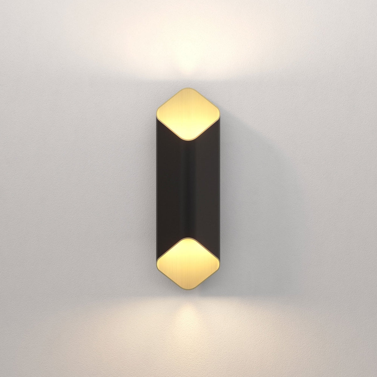 Black and gold wall sconce with light shining upwards and downwards on a white wall