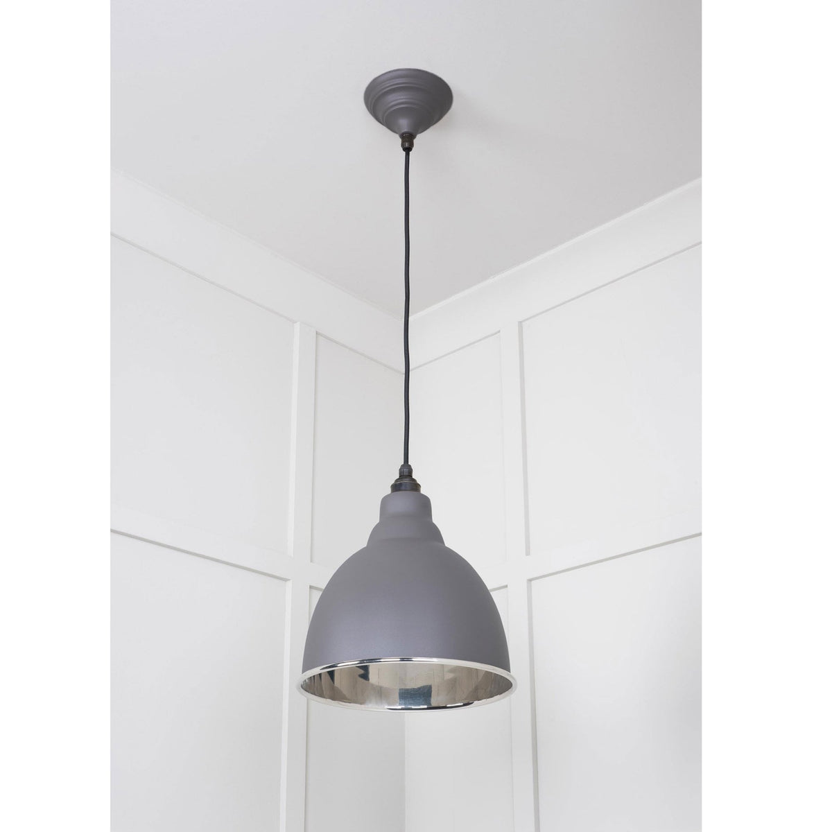 A dark grey dome-shaped pendant light with a silver interior, hanging in a room corner.