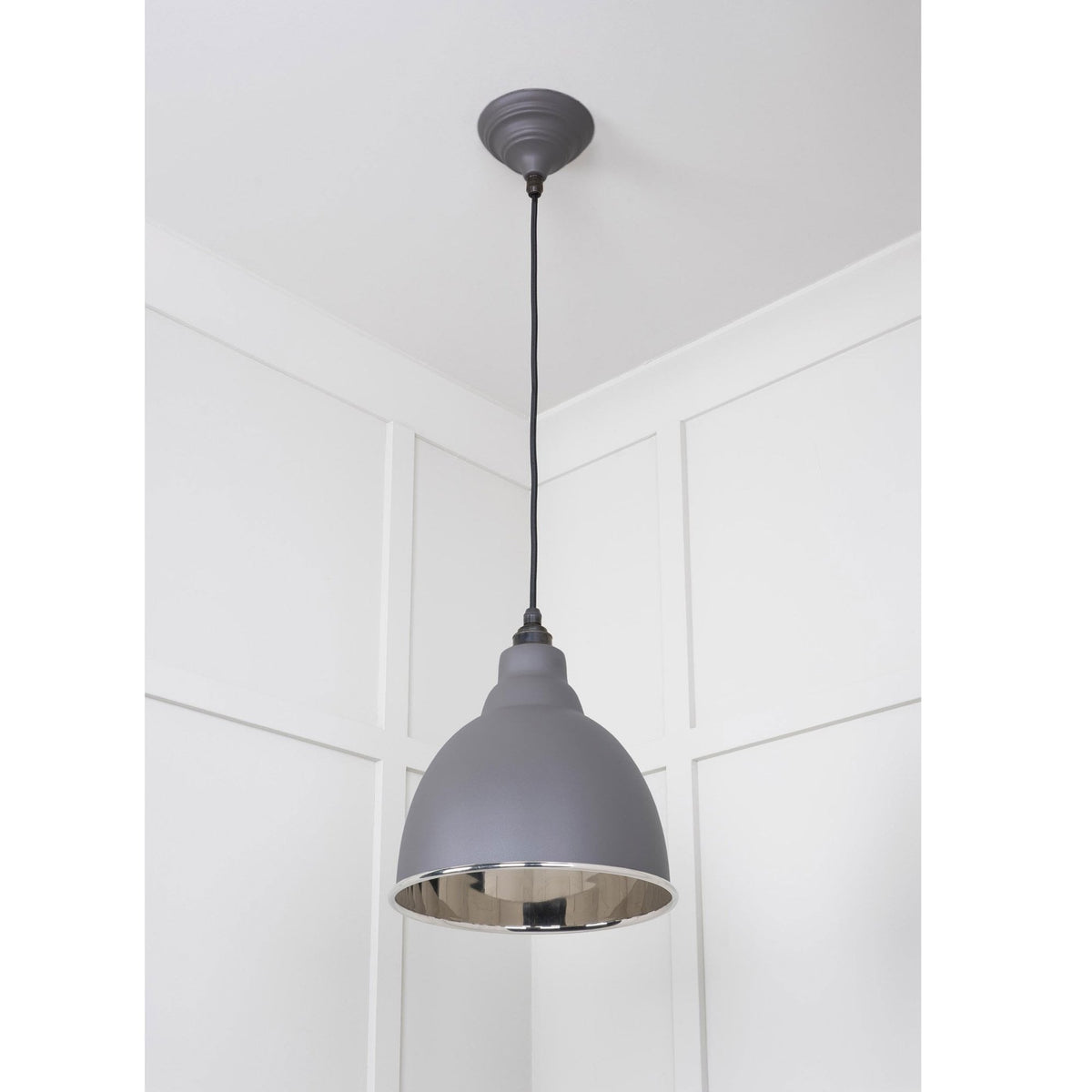 A dark grey dome-shaped pendant light with a silver interior, hanging in a room corner.