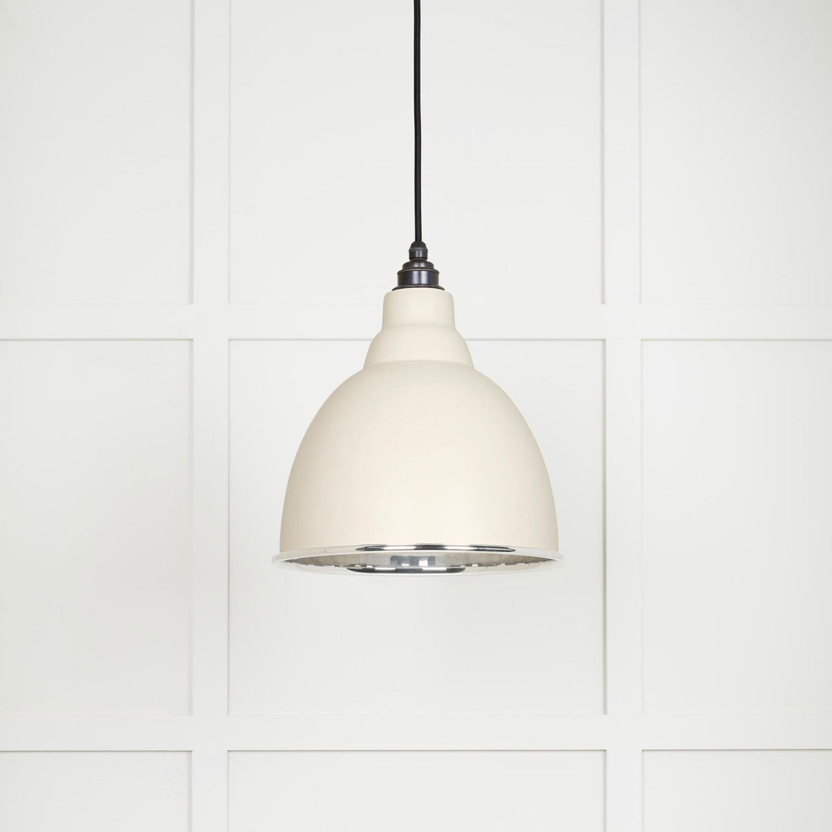 A close-up of a cream-coloured pendant light fixture with a silver interior.