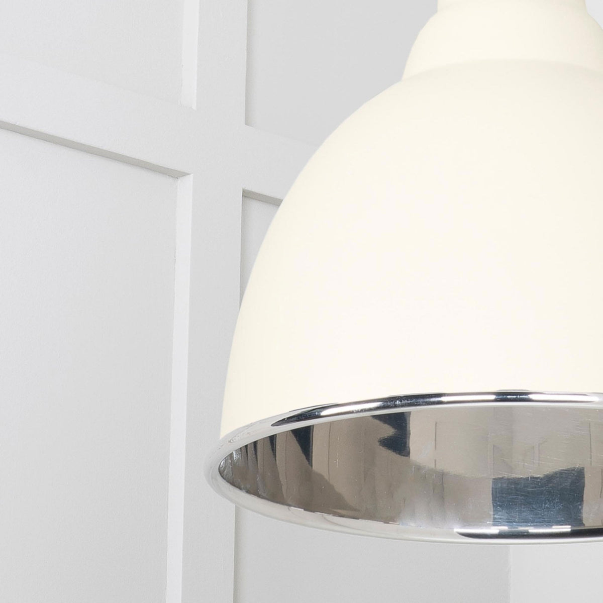 A close-up of the cream pendant light's silver interior and outer rim.