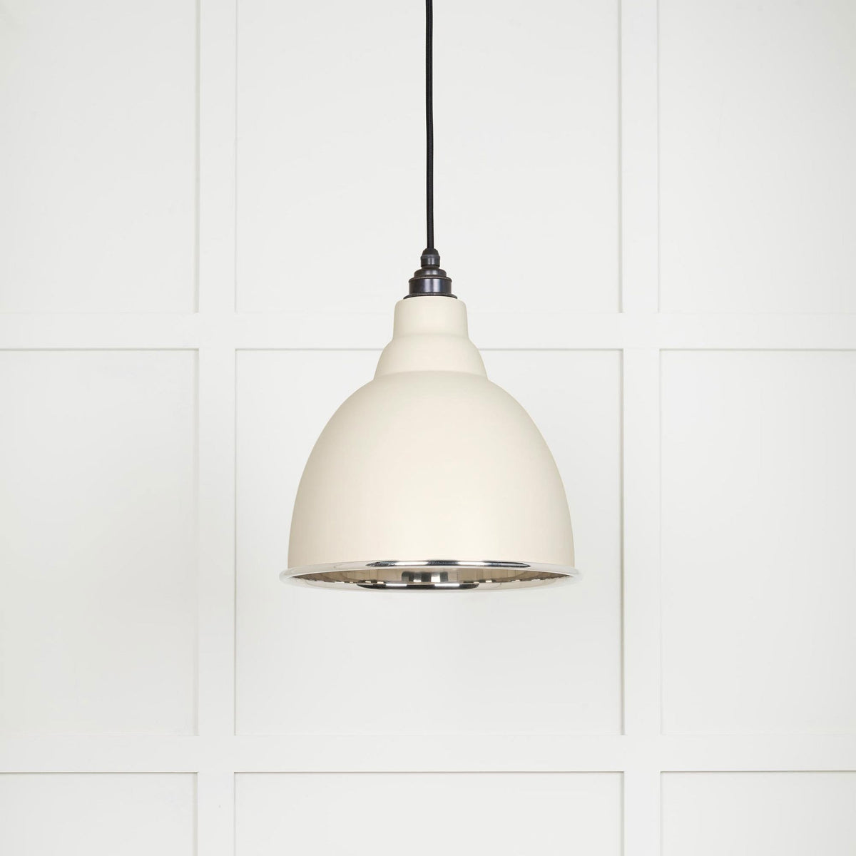 A cream-coloured pendant light fixture with a silver interior and black suspension.