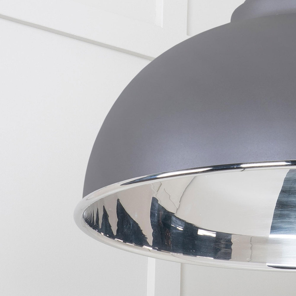 A close-up of the grey industrial pendant light's dome and reflective silver interior.