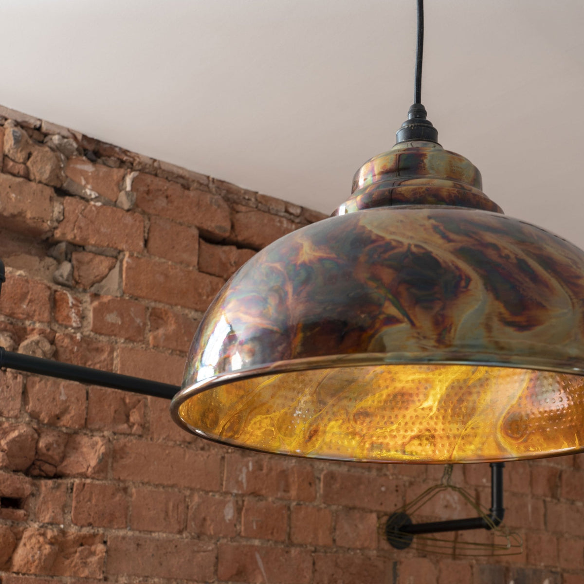 Close-up of the metallic iridescent dome pendant light with a warm glow within.