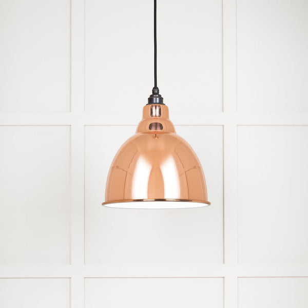 A close up of a shiny copper ceiling pendant light with a black cord.