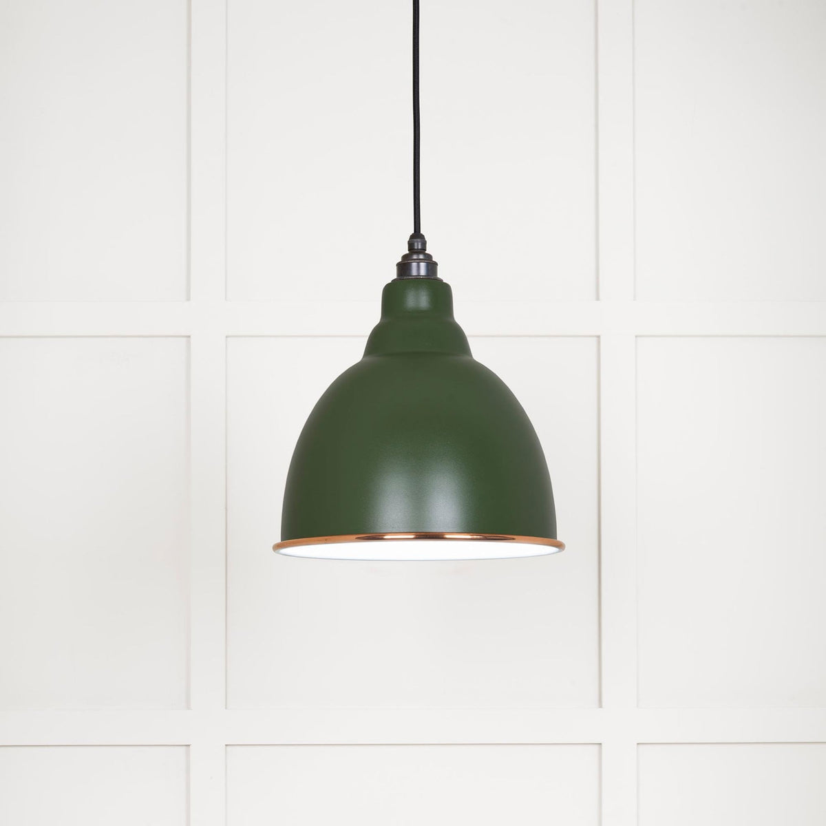 A close-up of a green industrial pendant light with a copper rim.