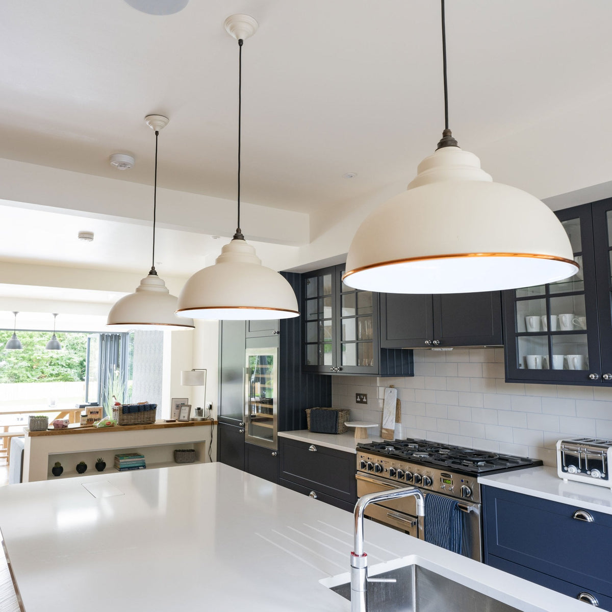Three white and copper pendant lights hanging over a kitchen island.