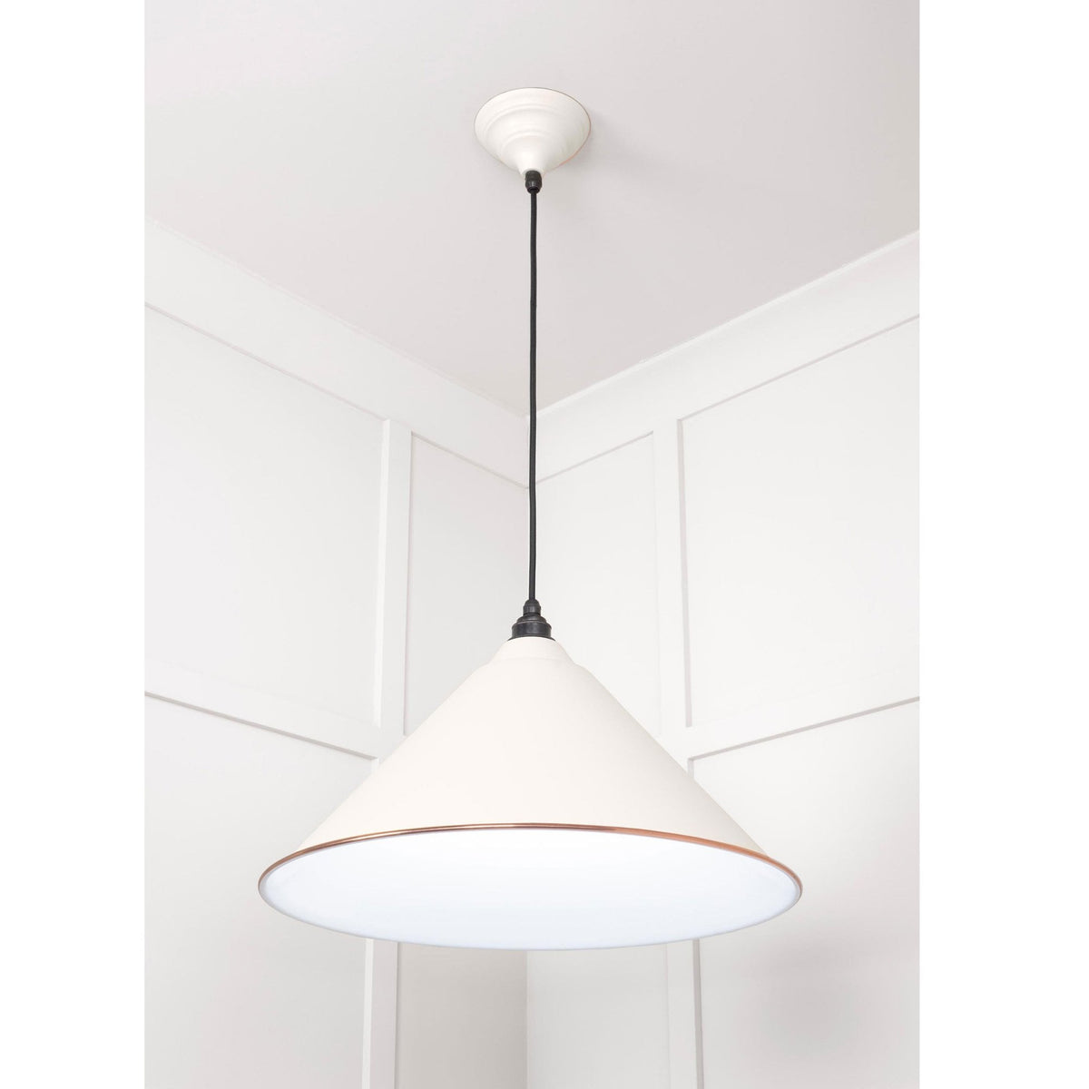 A white conical pendant light with a copper band hangs from a white ceiling against a white wall.