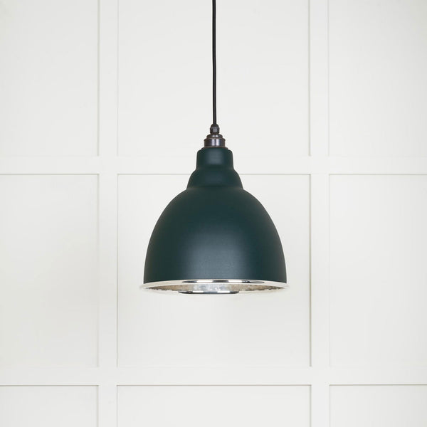 A close-up view of the pendant light, showcasing its dark green finish and silver interior. 
