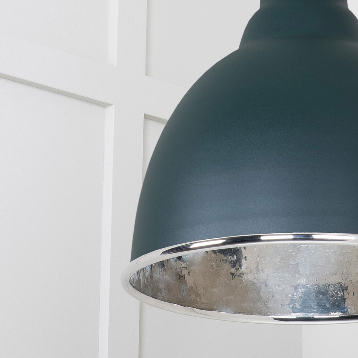 A detailed view of the pendant light's dome, highlighting the silver interior and metal rim. 