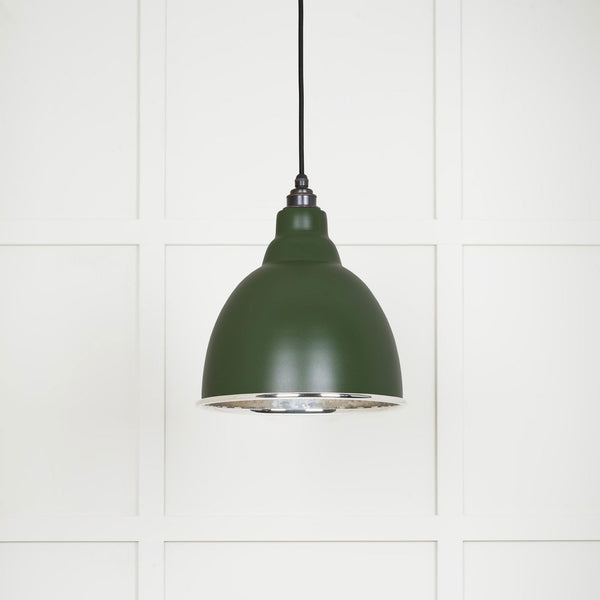 A close-up shot of a dark green pendant light with a silver interior.
