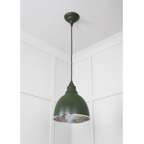 A dark green pendant light with a silver interior hanging from a ceiling.