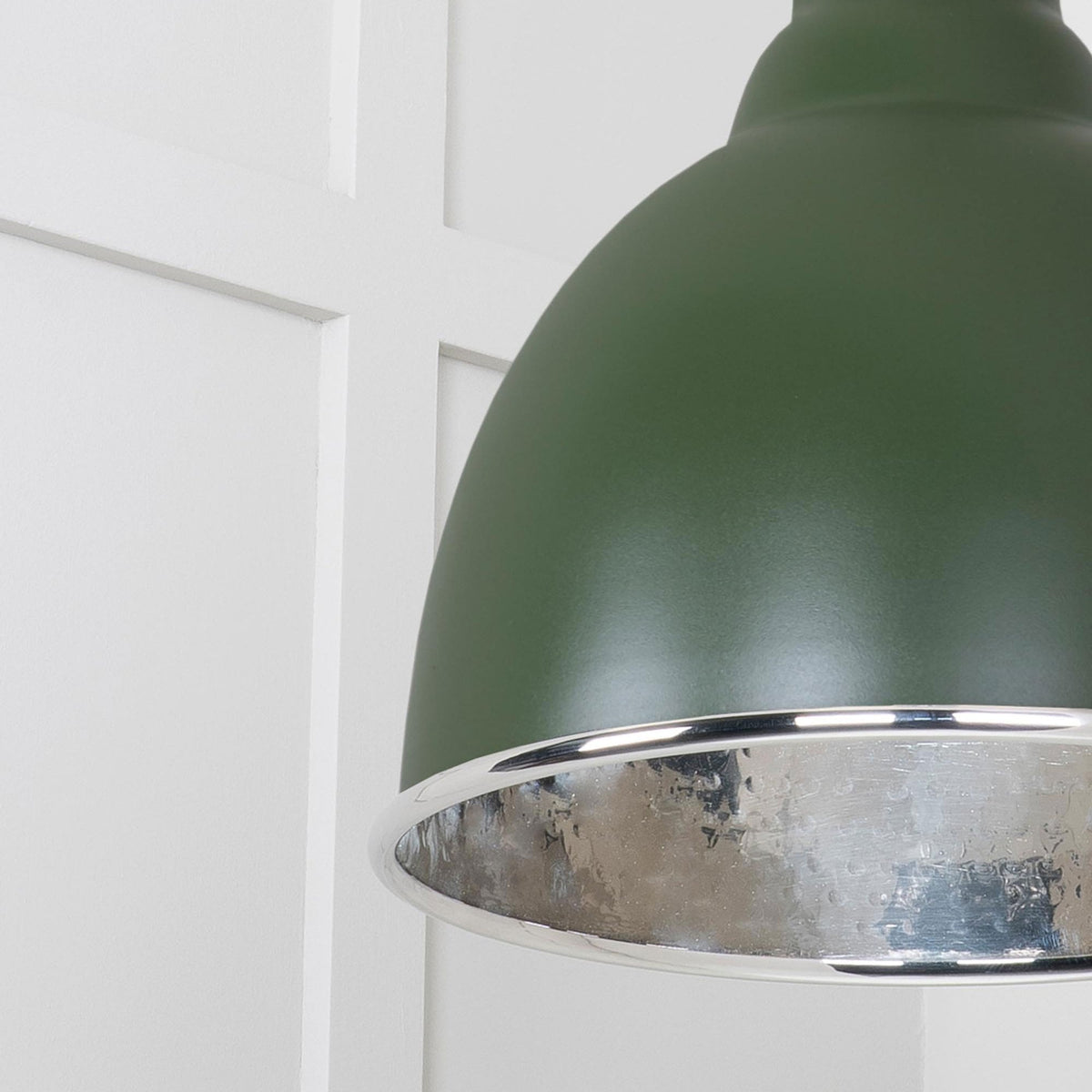 A close-up of the textured silver interior of a dark green pendant light.