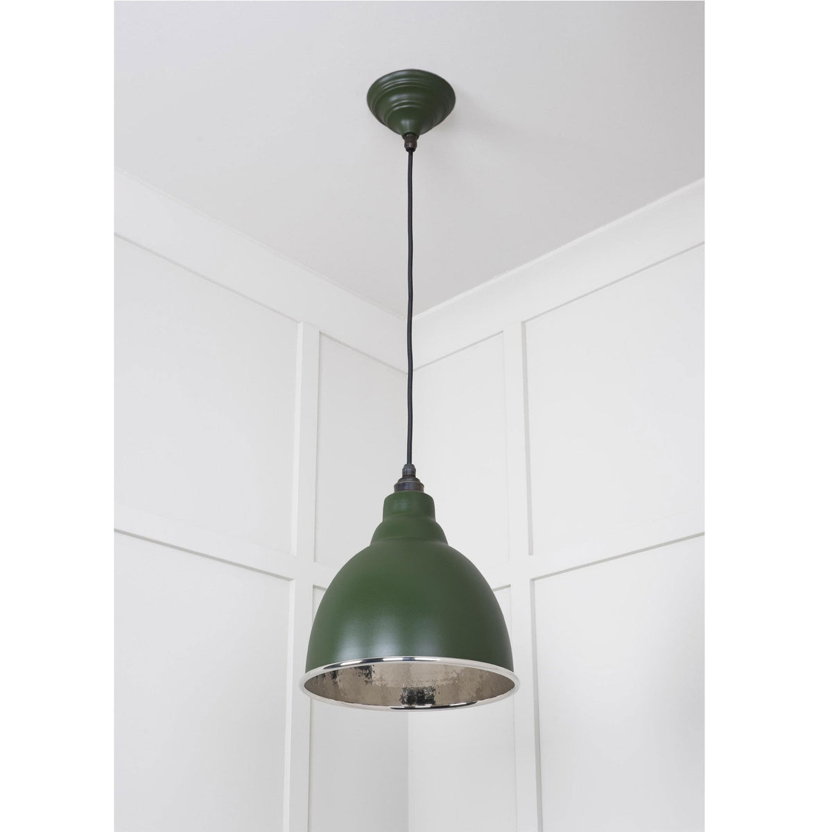 A dark green pendant light with a silver interior, hanging in a room corner.