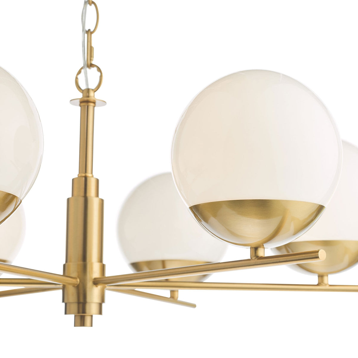 Close-up of a brass chandelier with five white globe lights, each with a brass base.
