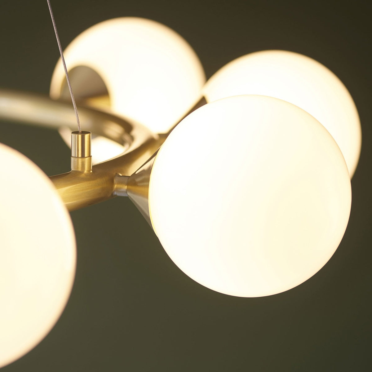 Close-up of a brass chandelier showing several glowing white globe light fixtures.