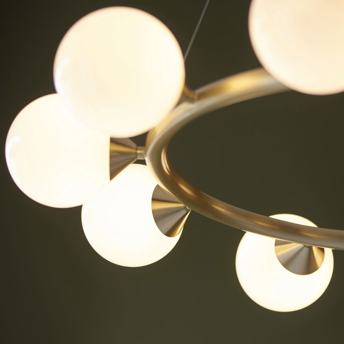 An upward-angled close-up of a brass chandelier with several glowing white globe lights.