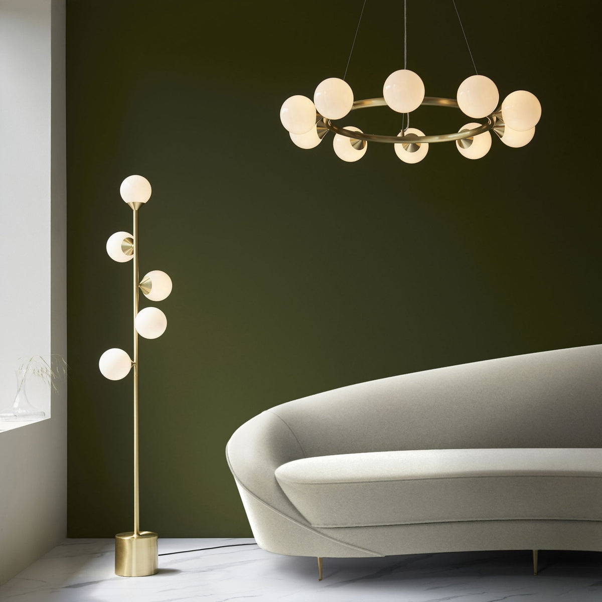 A brass chandelier and a matching floor lamp illuminate a modern living room with a white sofa.