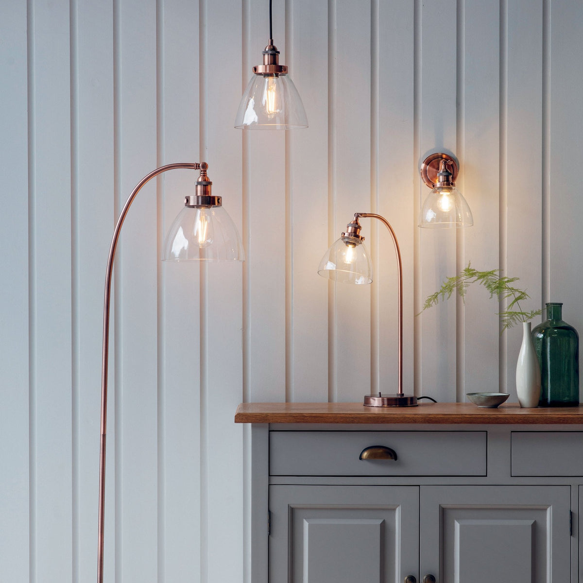 Matching copper lighting fixtures: a floor lamp, a pendant light, a table lamp, and a wall light in a room.