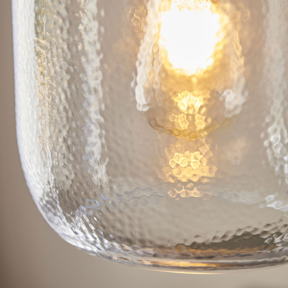 A detailed close-up of the hammered texture of a clear glass pendant light shade.