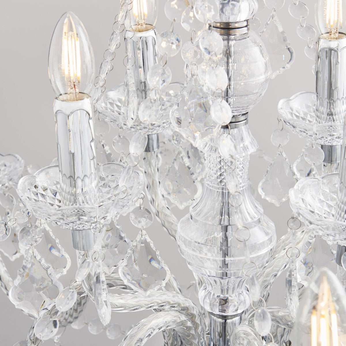 Close-up of a crystal chandelier showing a lit candle-style bulb and intricate glass details.