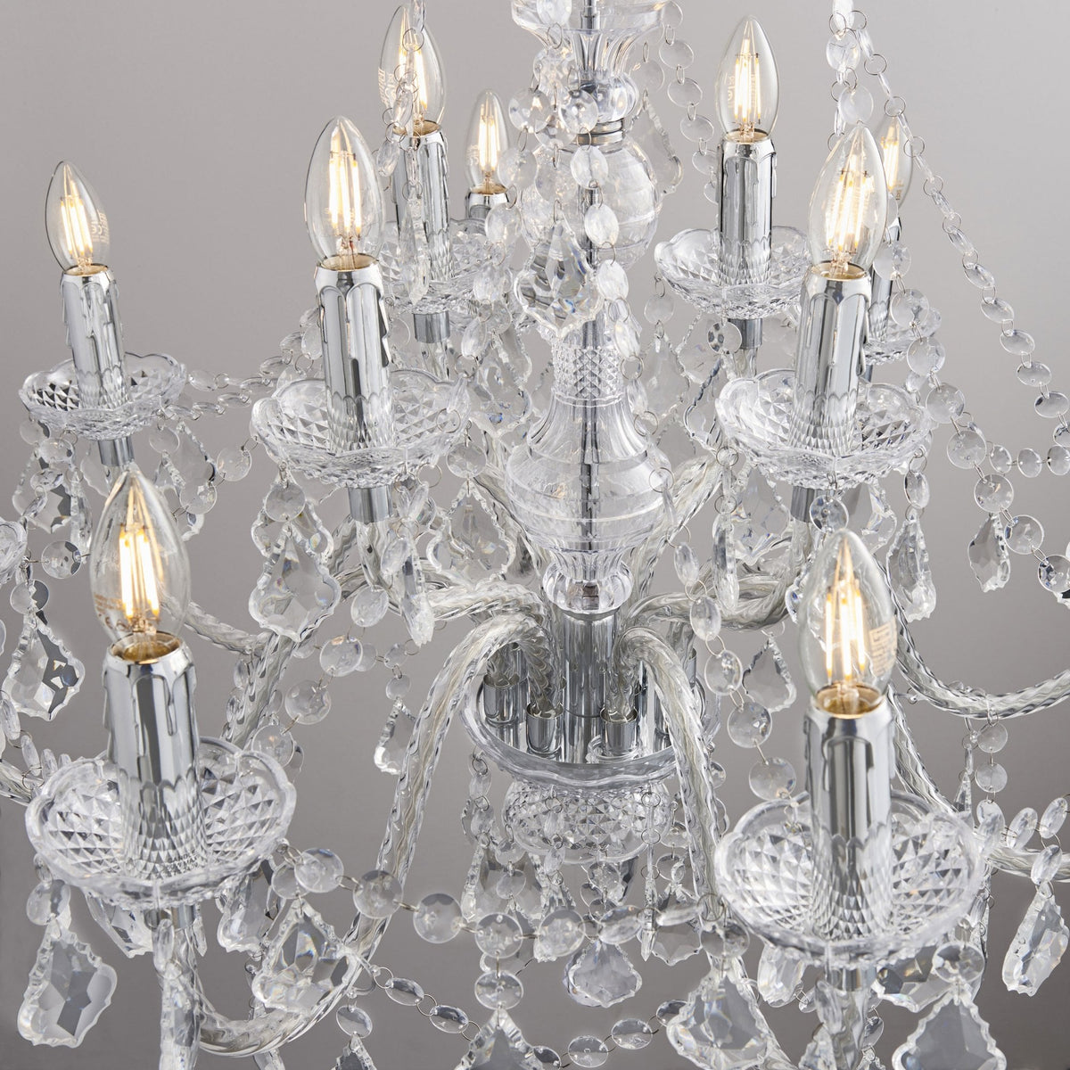 Close-up of a crystal chandelier showing several lit candle-style bulbs and intricate crystal details.