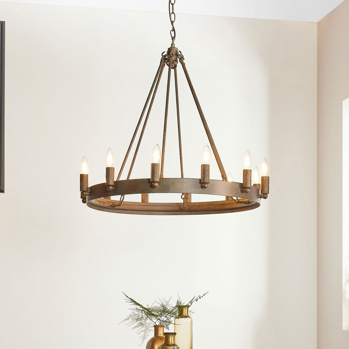 A large, round, rustic bronze chandelier with eight exposed candle-style bulbs hangs from a ceiling.
