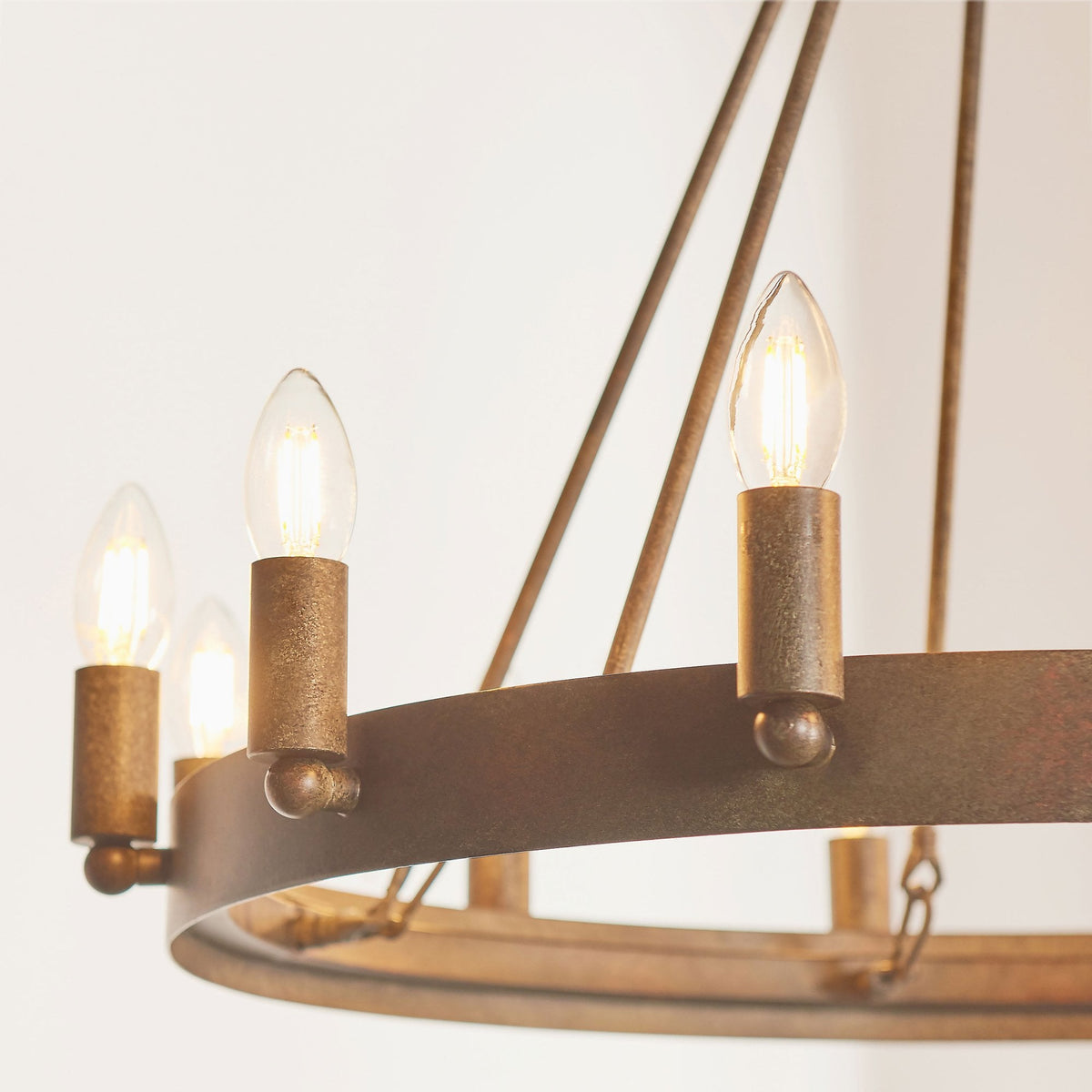Close-up of the rustic bronze chandelier showing three illuminated candle-style bulbs and the textured metal finish.