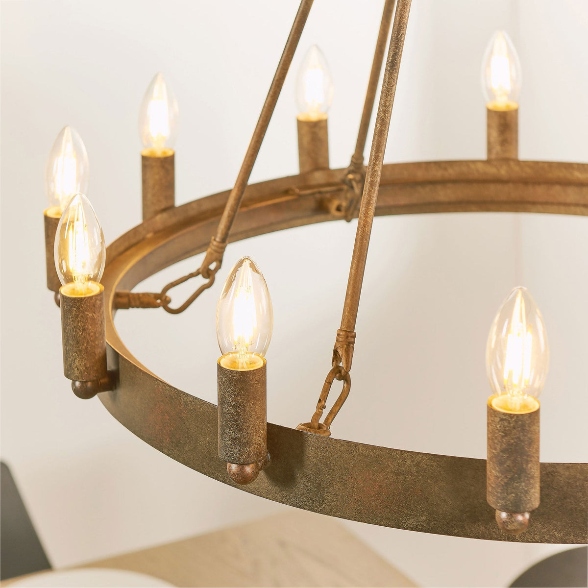 Angled view of the rustic bronze chandelier, showcasing multiple illuminated candle-style bulbs and the metal frame.