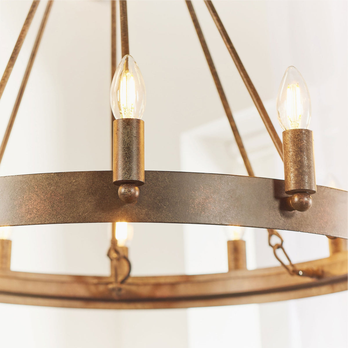Close-up of two illuminated candle-style bulbs on the rustic bronze chandelier, emphasizing the aged metal look.