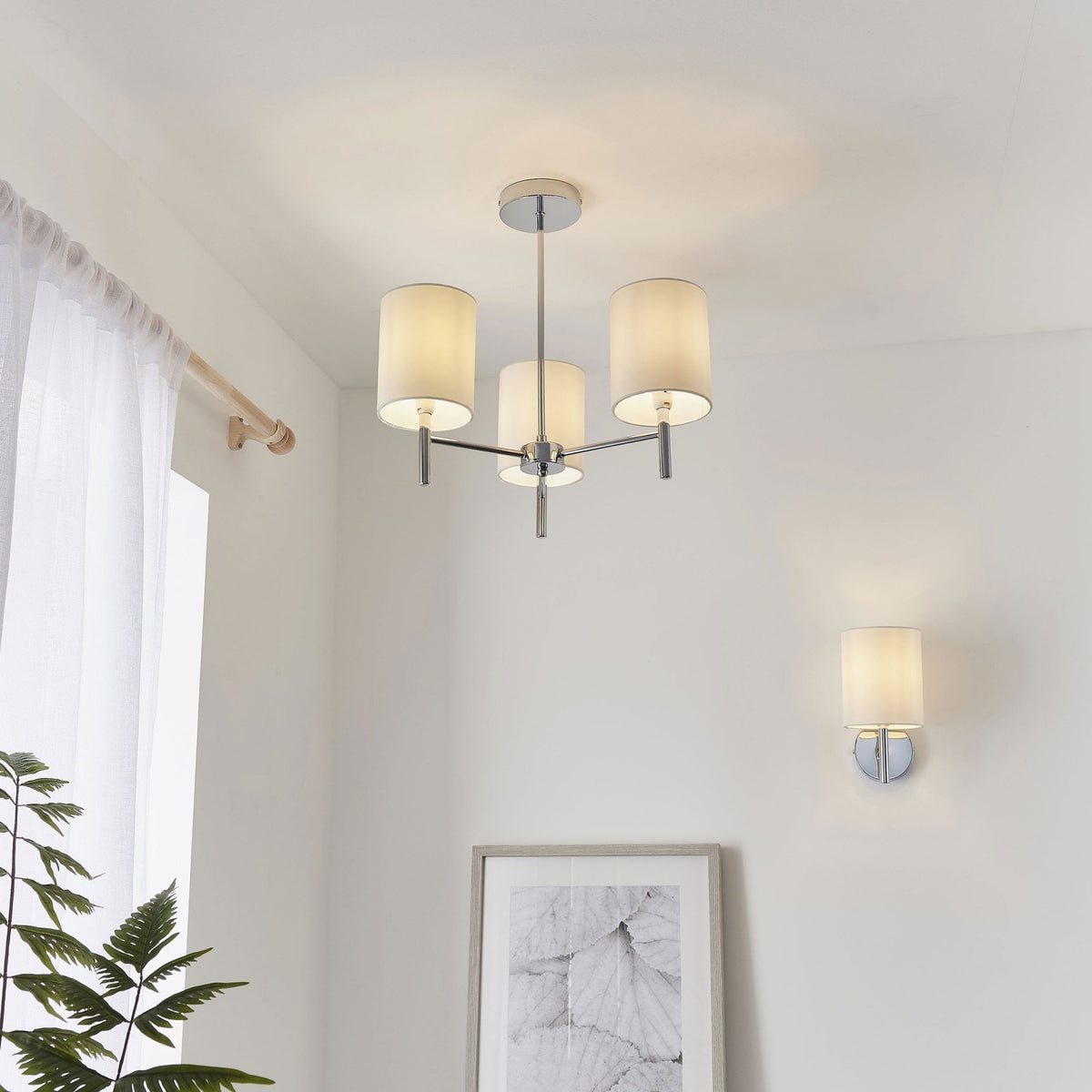 Chrome ceiling light with three white cylindrical shades and a matching wall light.