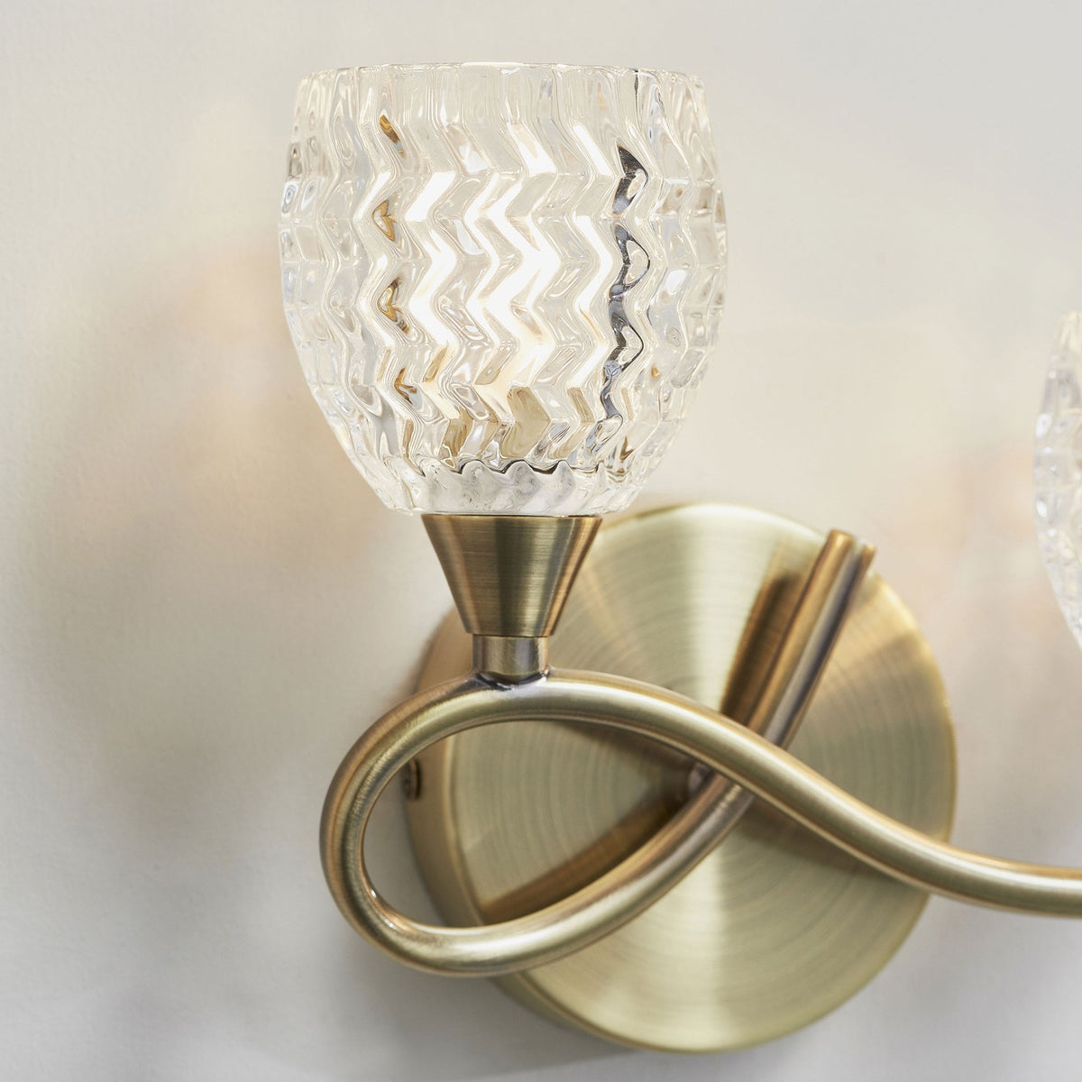 Close-up of a single light on an antique brass wall sconce with a clear, textured glass shade.