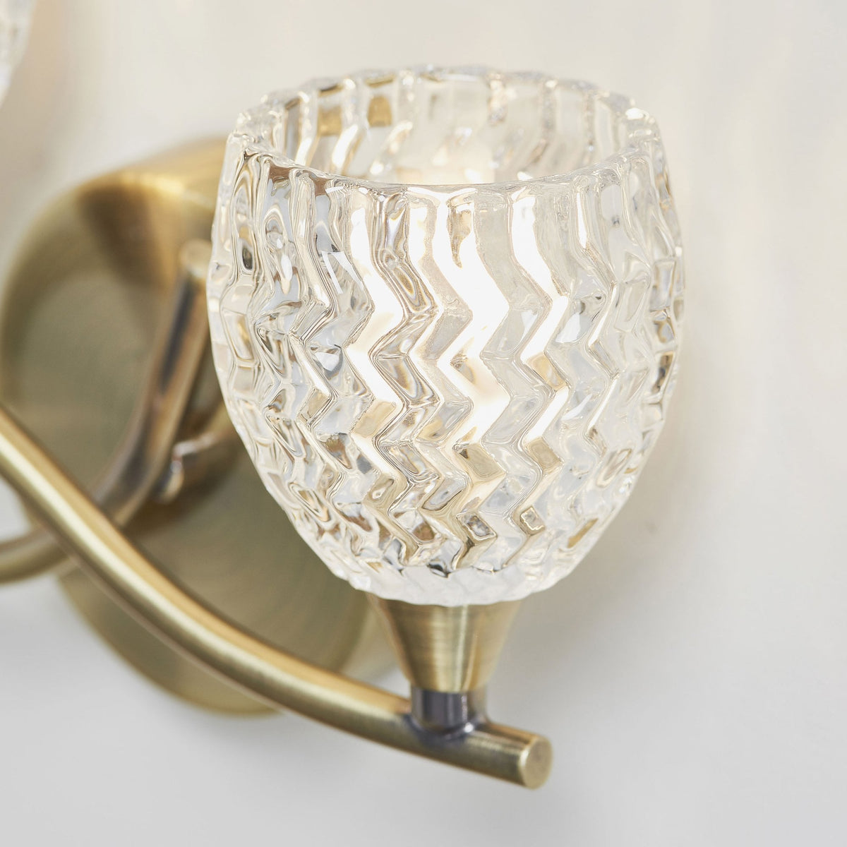 Close-up of a clear, textured glass shade on an antique brass wall sconce.