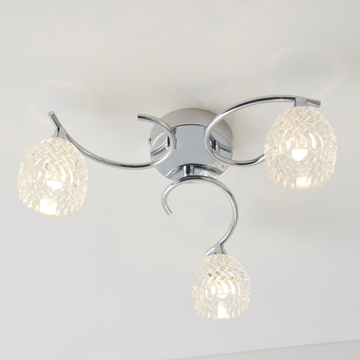 Three-light ceiling fixture with chrome arms and textured glass shades.
