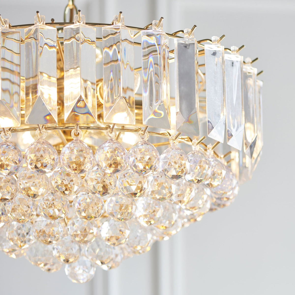 Detailed view of the gold frame and clear crystal elements of a chandelier.
