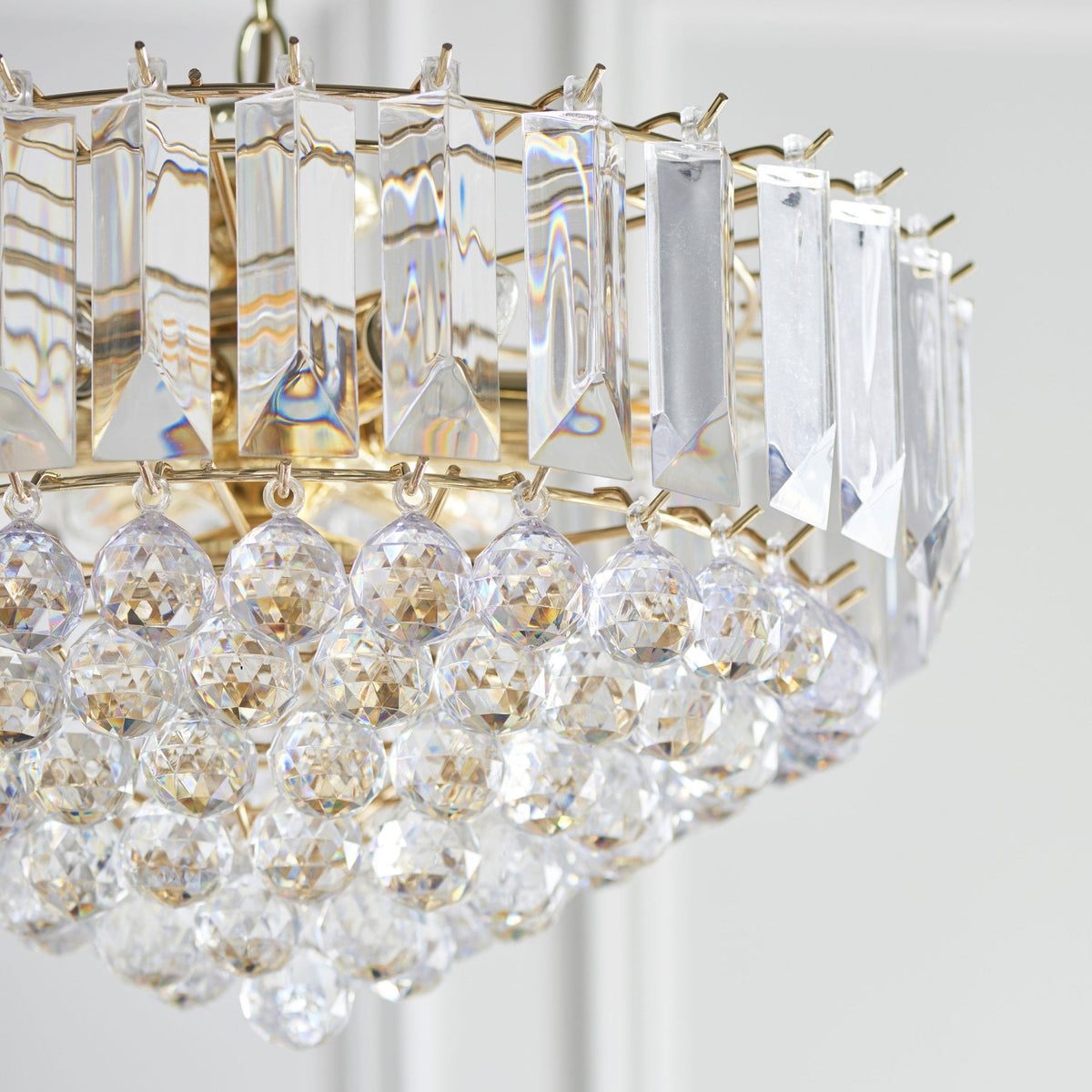 Angled close-up of the sparkling crystal and gold details of a chandelier.