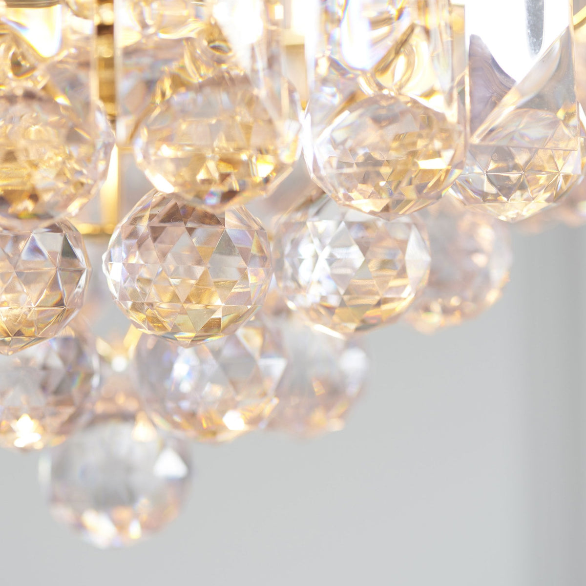 A close-up of the chandelier shows the gold chain and the crystal details.
