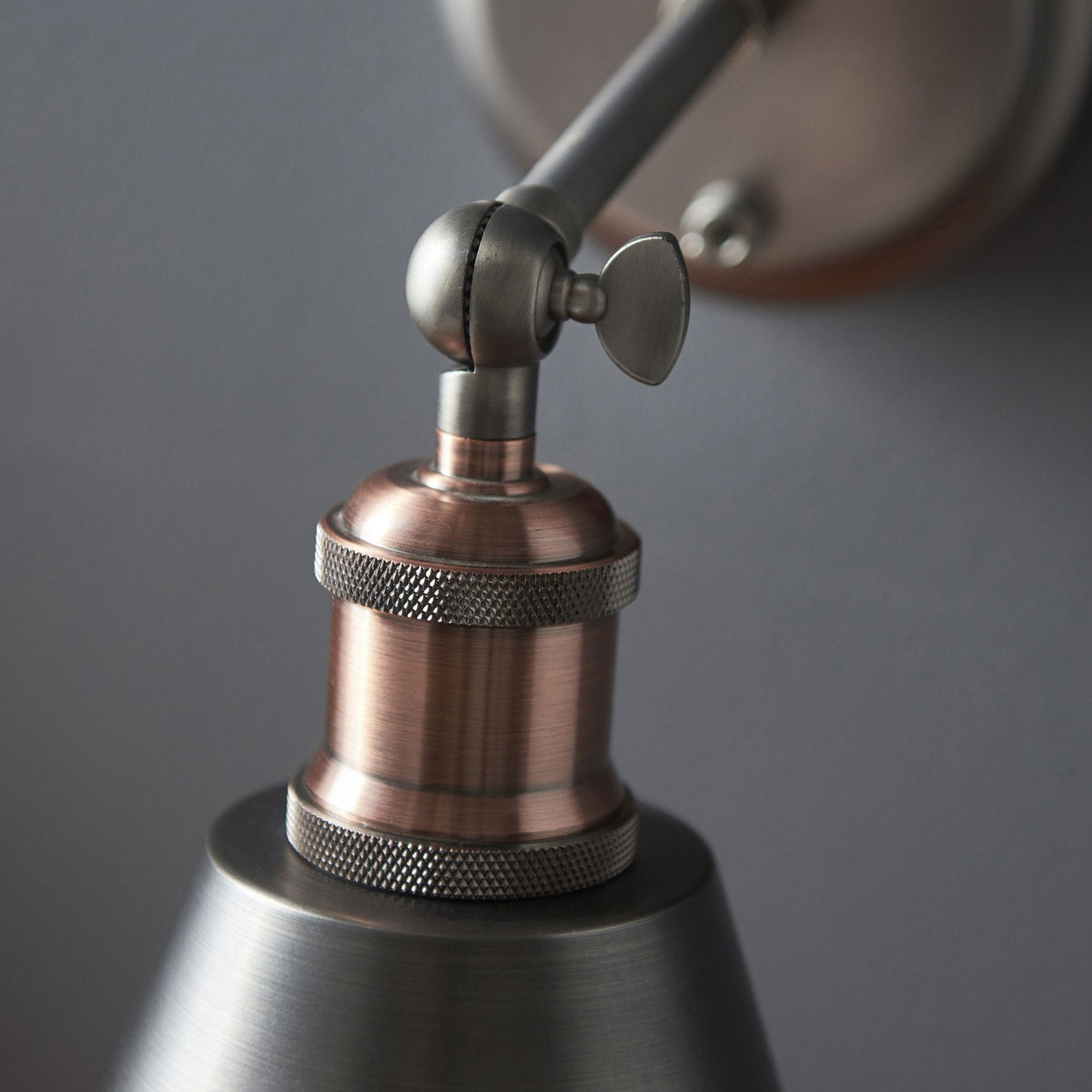 Close-up of the wall light's copper and brushed metal joint, showing textured details.