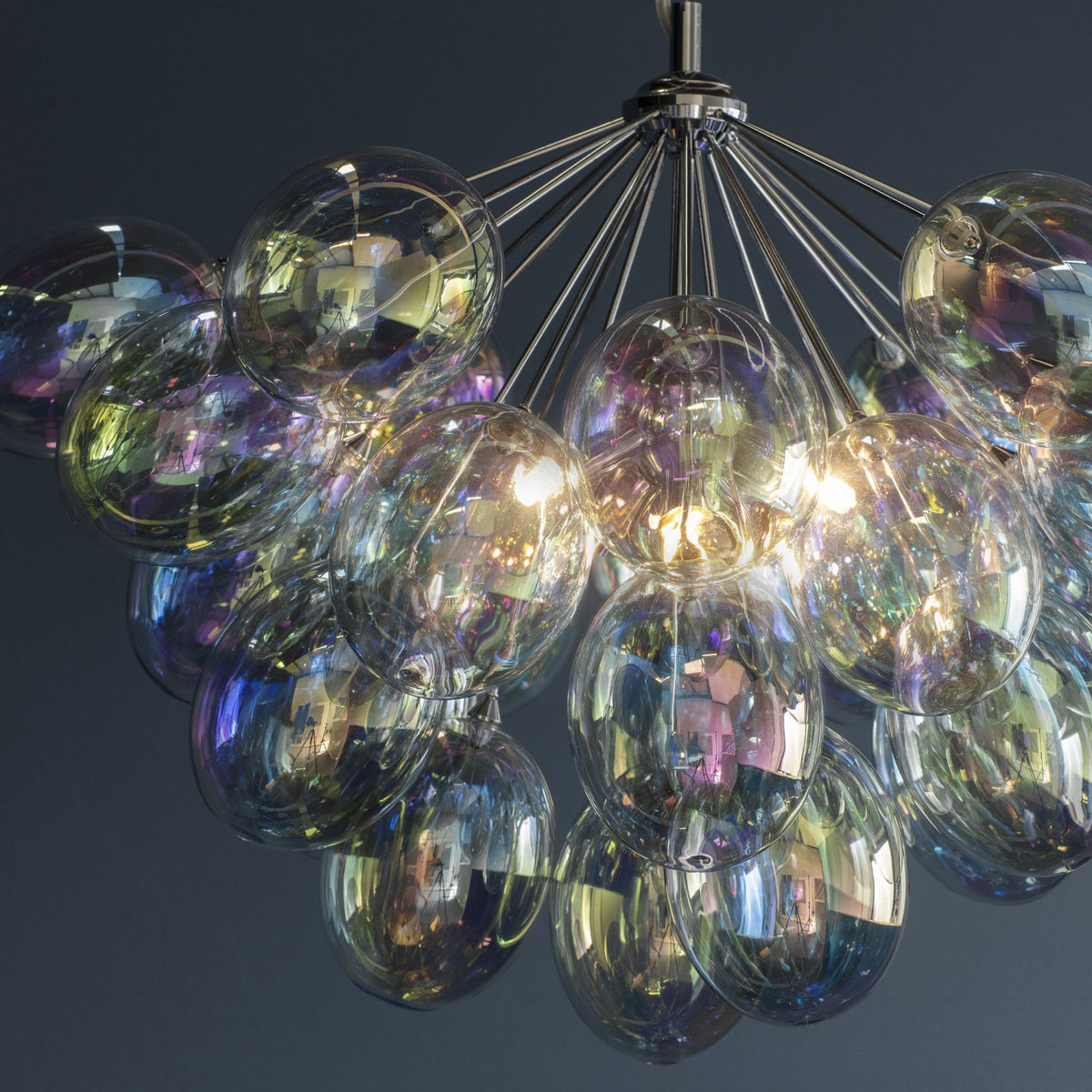 Close-up of a chandelier with numerous iridescent glass shades, reflecting various colors.