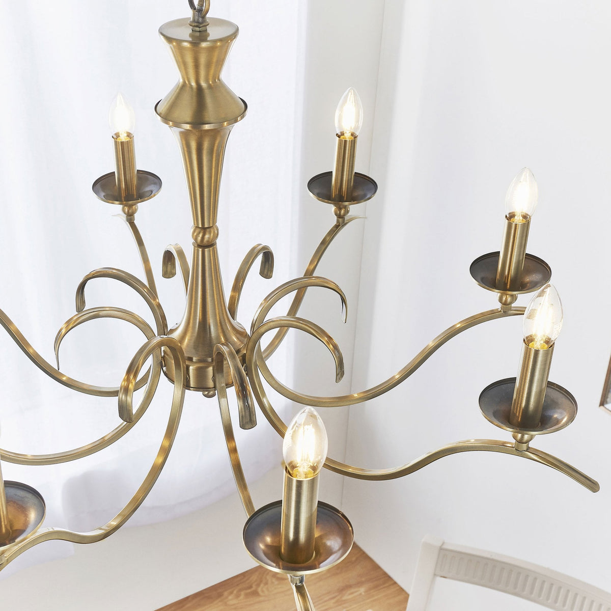 Close-up of an antique brass chandelier with eight candle-style bulbs, viewed from above.