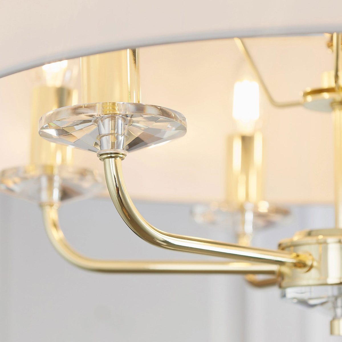 Detailed view of a gold arm and crystal bobeche on the chandelier.