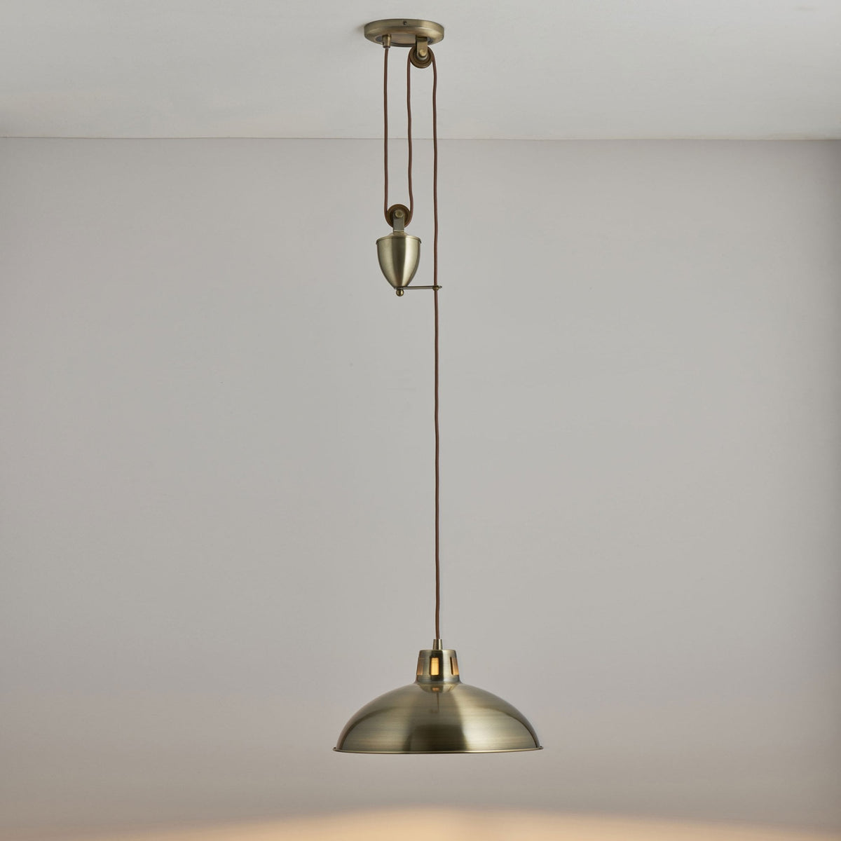 A brass pulley pendant light with a dome shade hangs from the ceiling.